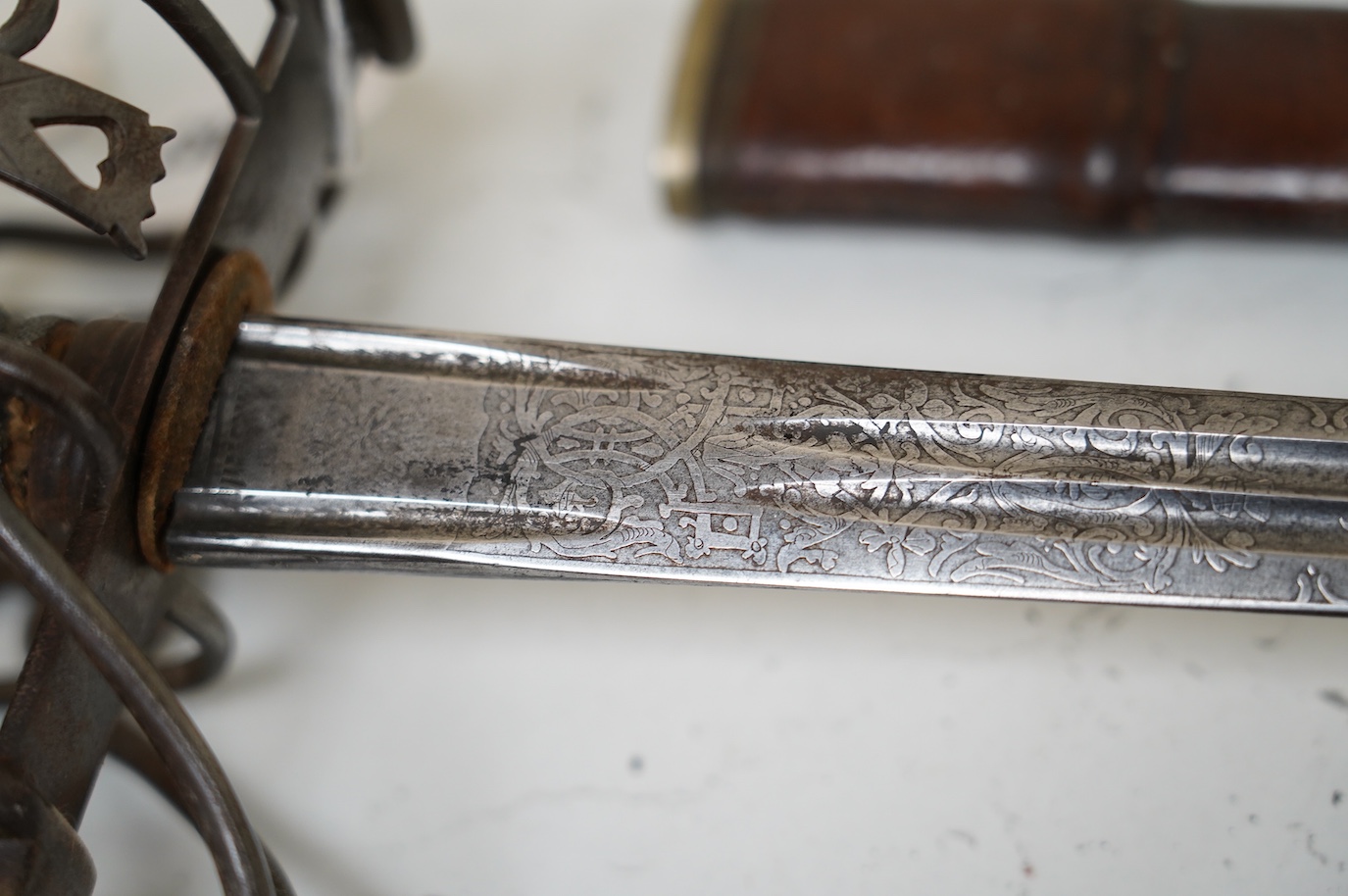 A late Victorian officer’s sword of the Black Watch, claymore blade etched with regimental title and VR cipher, regulation basket hilt, fish skin covered grip, in its leather covered field service scabbard, blade 82cm. C
